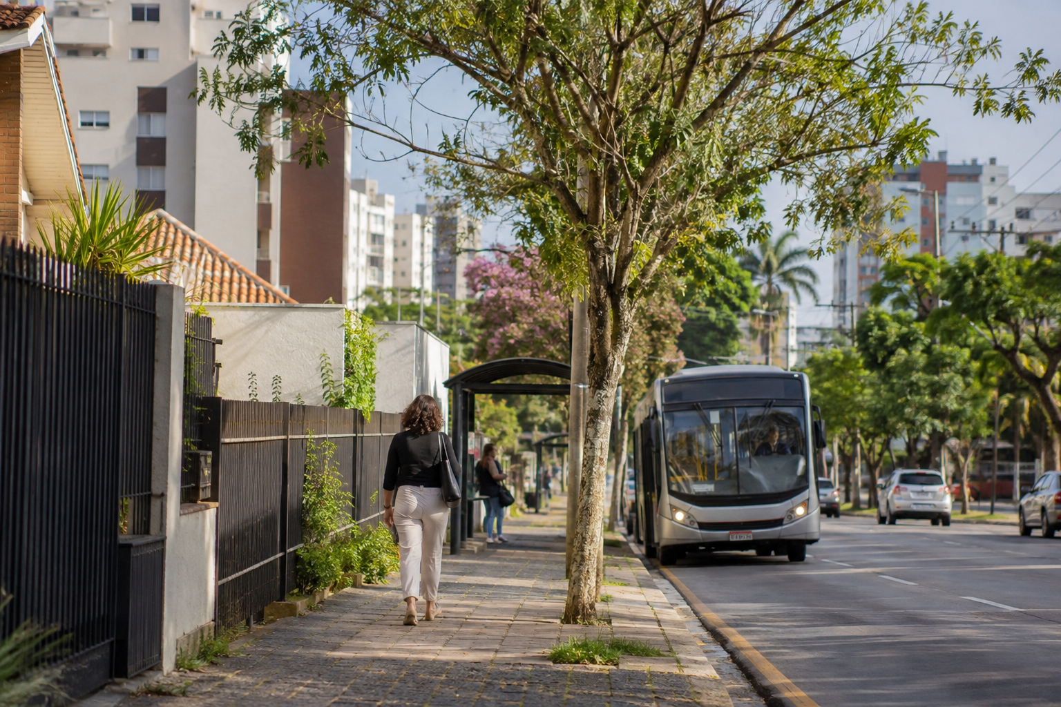 Rua residencial com prédios, casas e transporte coletivo próximo às moradias.