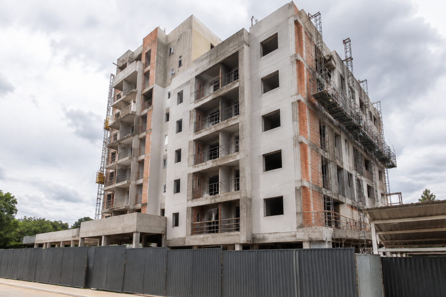 Fotografia documental realista de edifício residencial brasileiro ainda em obras, fachada parcialmente concluída, andaimes e acesso fechado